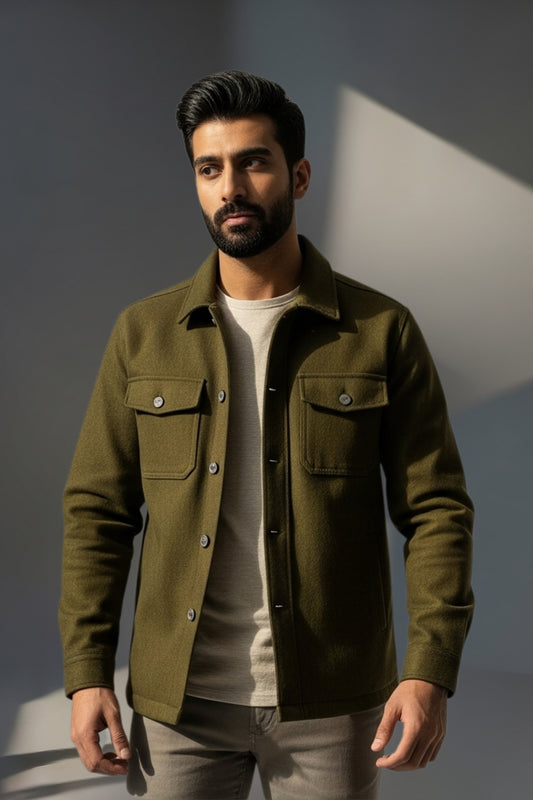 Man wearing a green jacket over a white shirt against a gray background