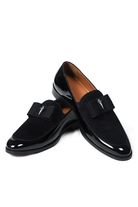 Pair of black loafers with bow details on a white background