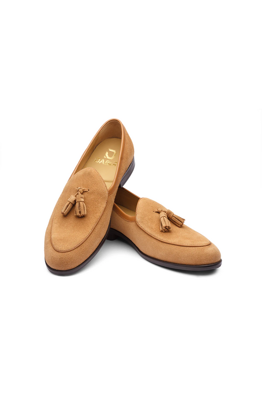 Pair of tan loafers with tassels on a white background