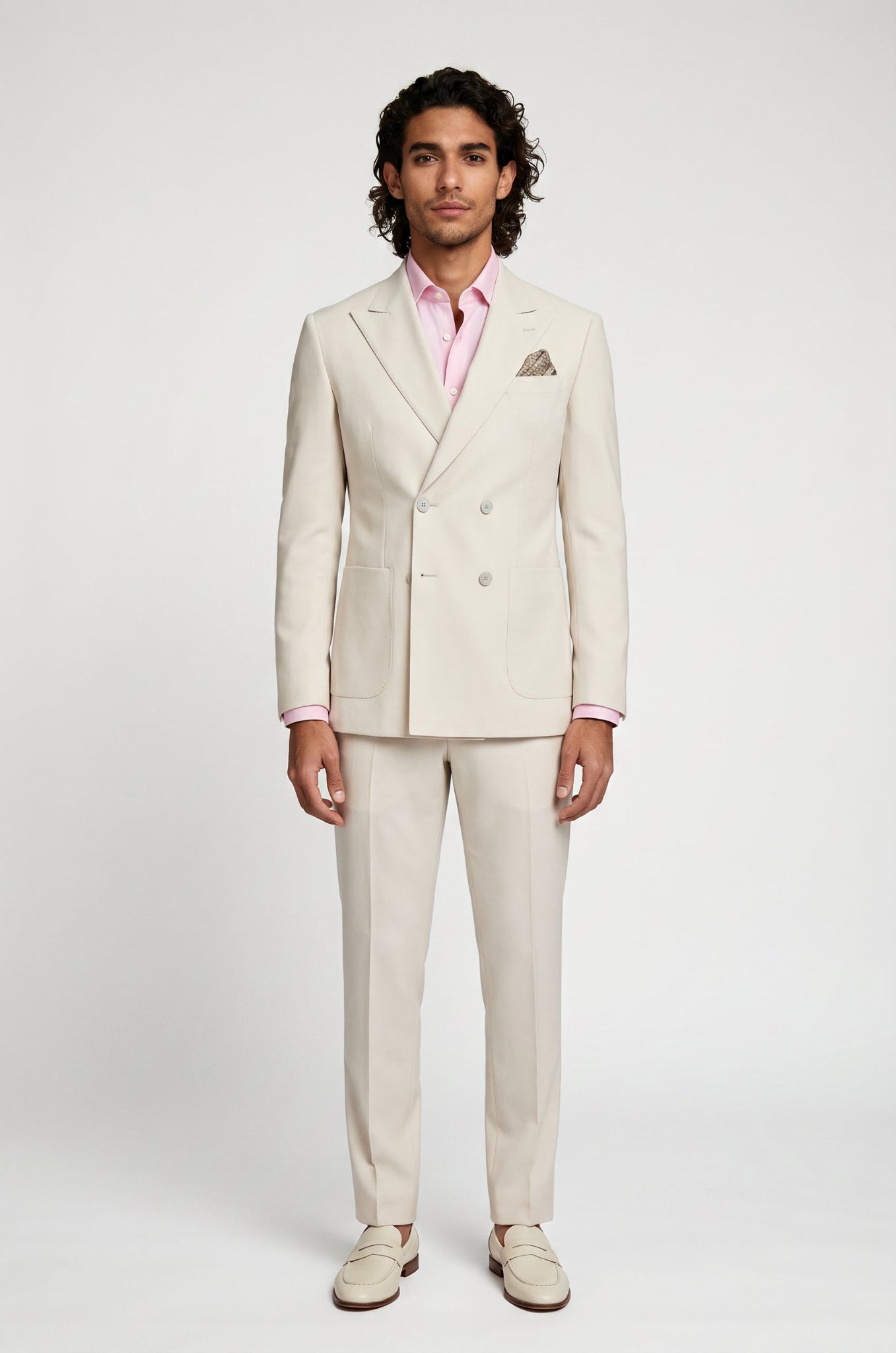Man wearing a light beige suit with a pink shirt on a white background