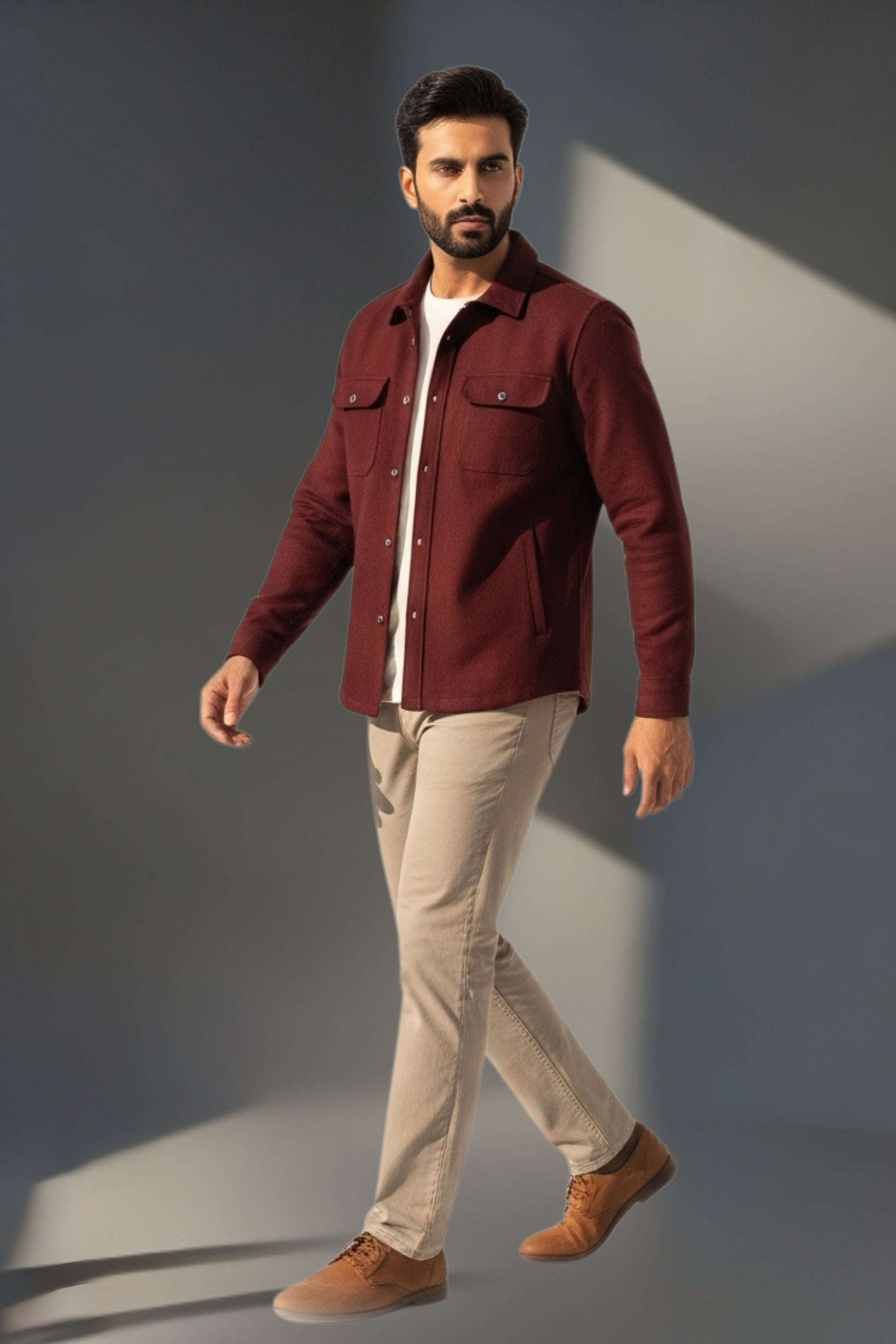 Man wearing a burgundy jacket and beige pants against a gray background