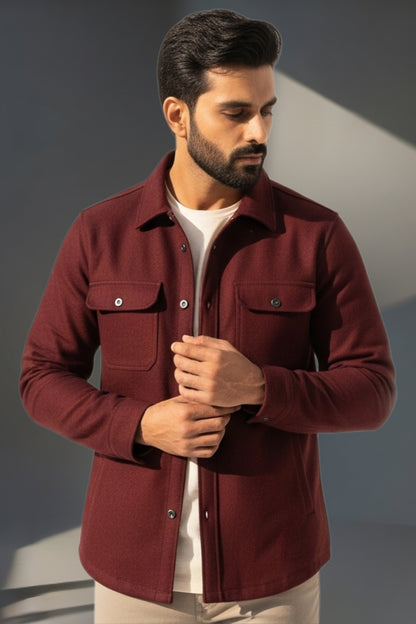 Man wearing a burgundy jacket against a gray background