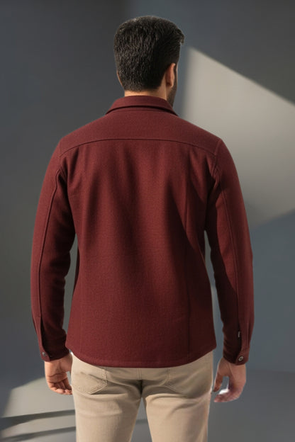 Man wearing a maroon jacket and beige pants against a gray background