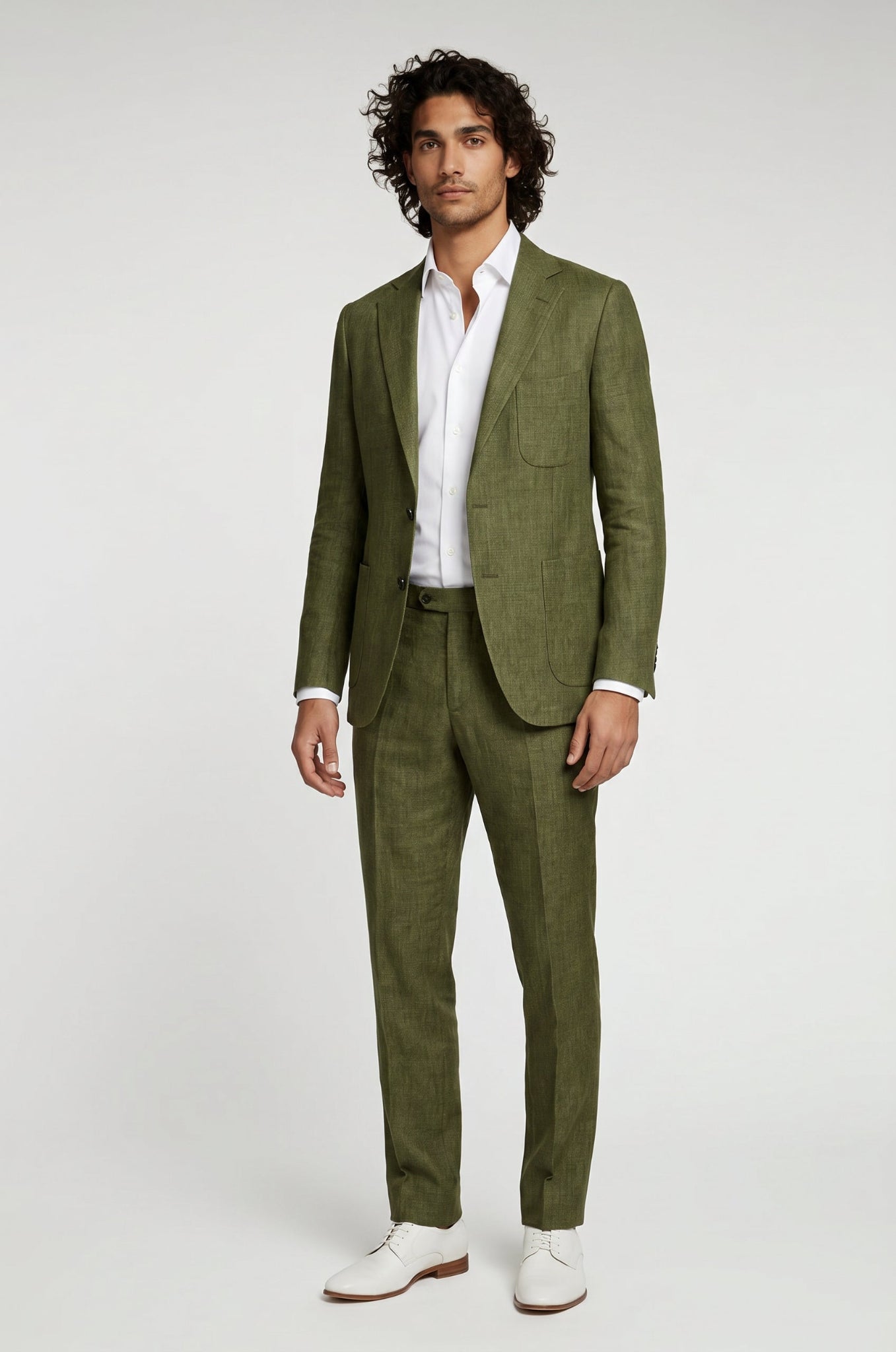 Man wearing a green suit with a white shirt and white shoes on a light gray background