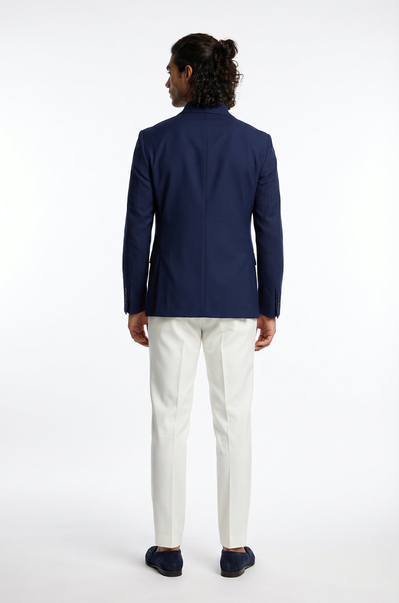 Man wearing a navy blazer and white pants on a white background