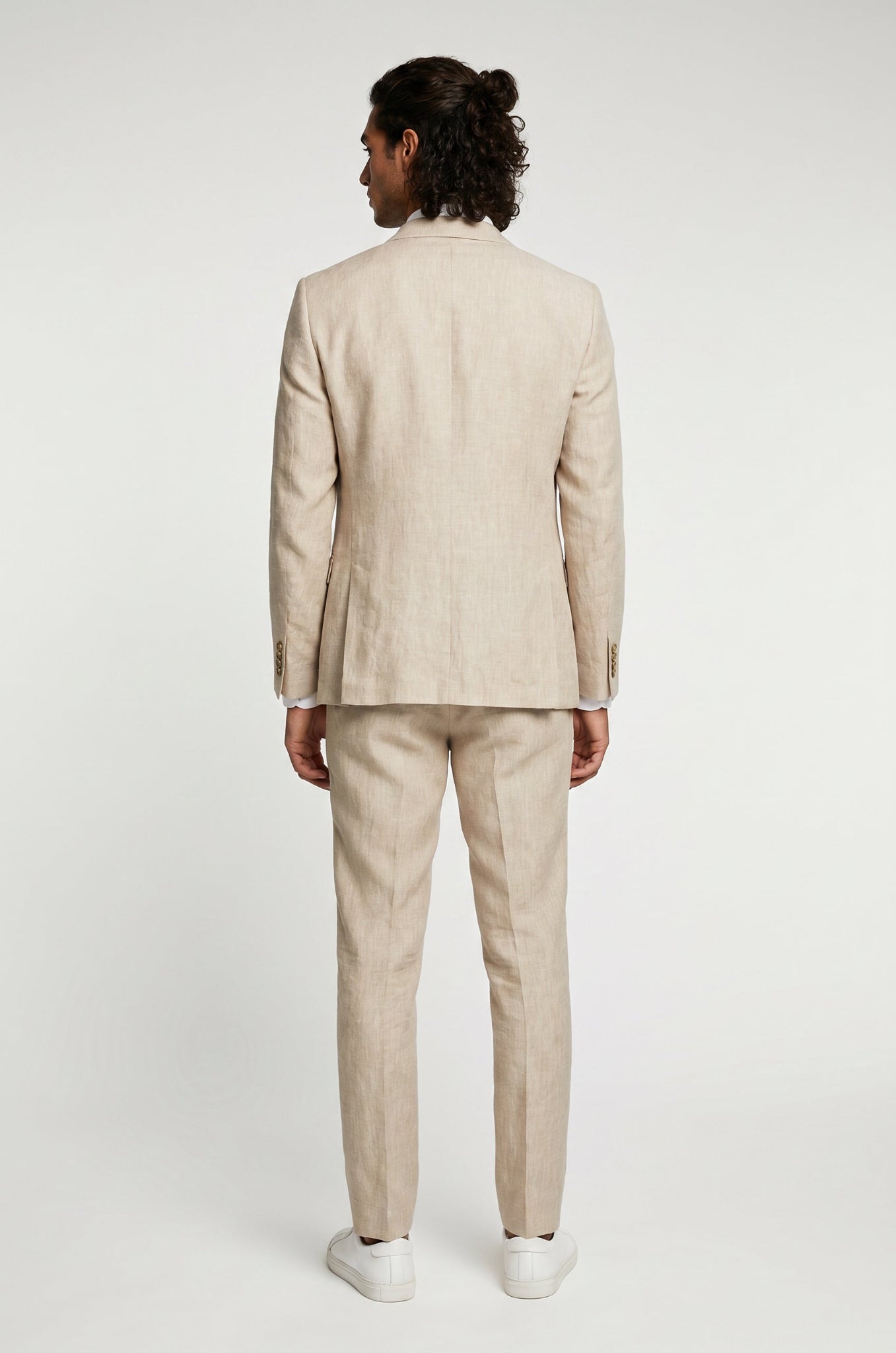 Man wearing a beige suit standing against a white background
