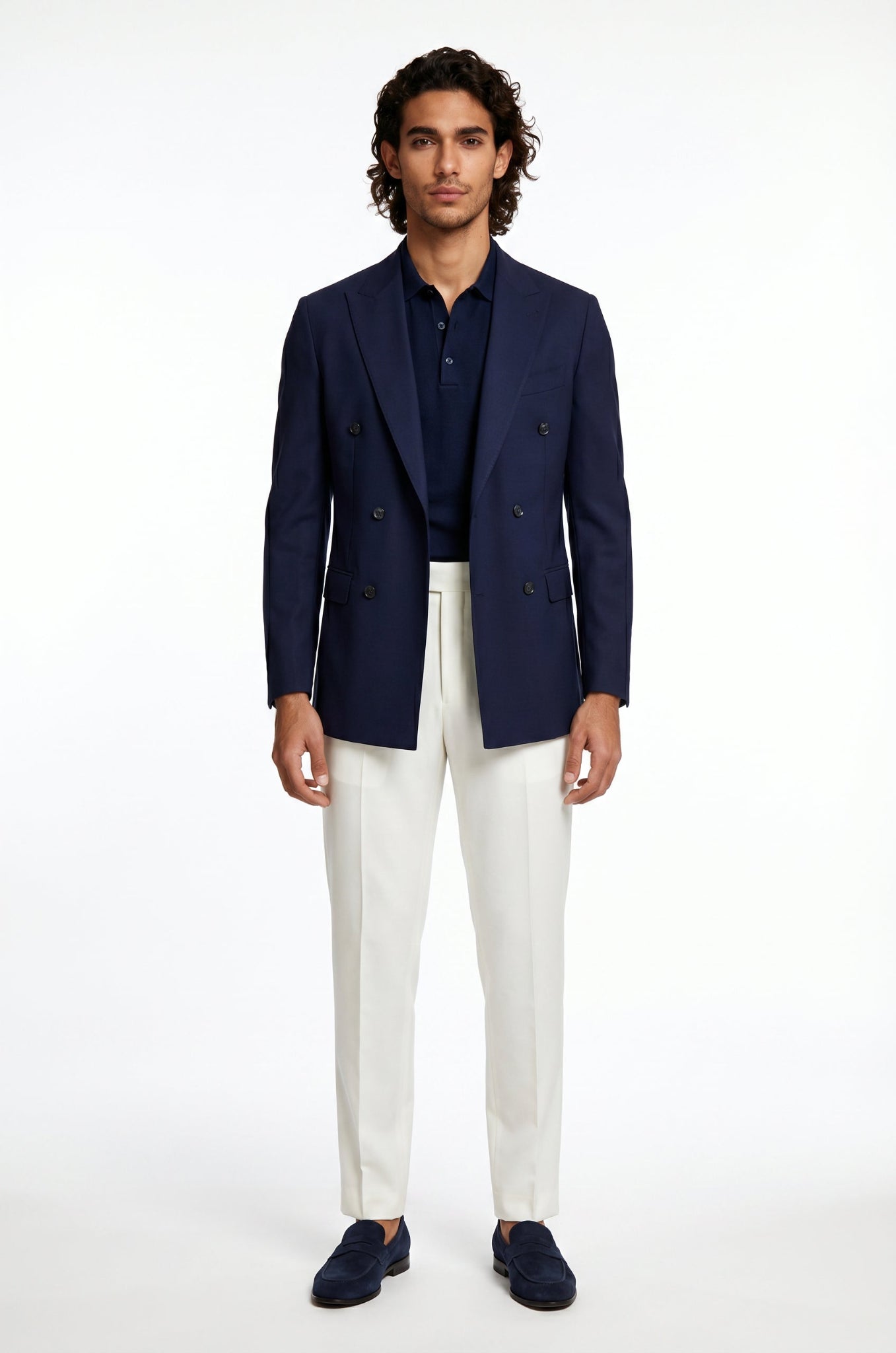 Man wearing a navy blazer, white pants, and dark shoes on a white background