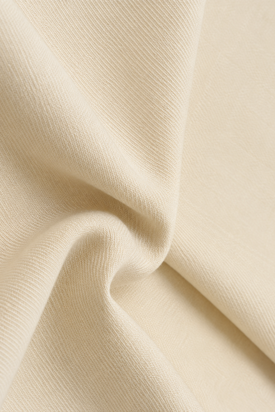 A close-up of draped cream-colored fabric with a fine ribbed texture, showing soft folds and shadows.